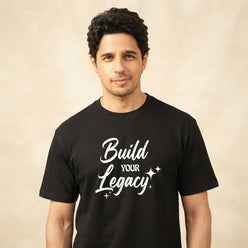 Siddharth Malhotra wearing a black cotton T-shirt with a white brush-style quote in a professional editorial portrait.